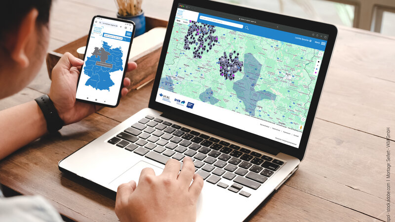 Junger Mann vor dem Laptop mit Smartphone in der Hand. Auf beiden Bildschirmen ist die Webseite von Sicher in meiner Region zu sehen.